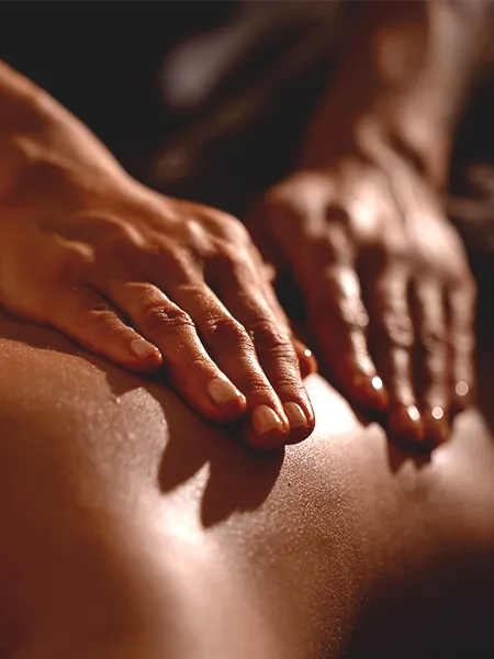 Close up of fingers caressing the back of a client back lathered with essential oils, peforming the "Vita Flex" method.