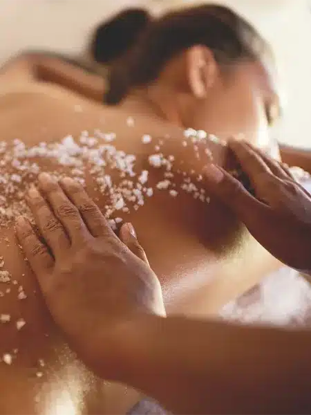 Close up of man massage a woman's back with salt scrub therapy.