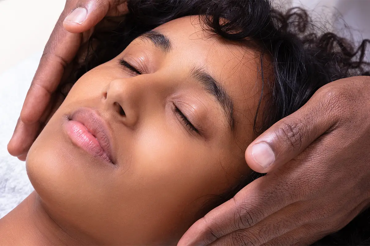 A woman with hands over her ears for a reiki massage.