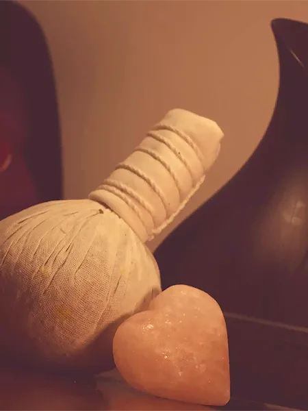 A Thai poultice and a heart shaped Himalayn hot stone sitting in front of a diffuser.