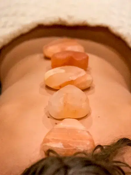 Heart shaped Himalayan hot stones resting on a laying woman's back.