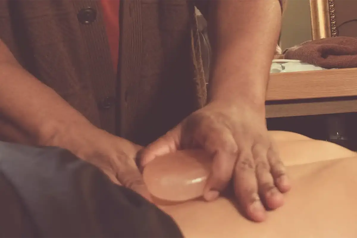 Johaun placing a Himalayan salt hot stone gently on a client's lower back.