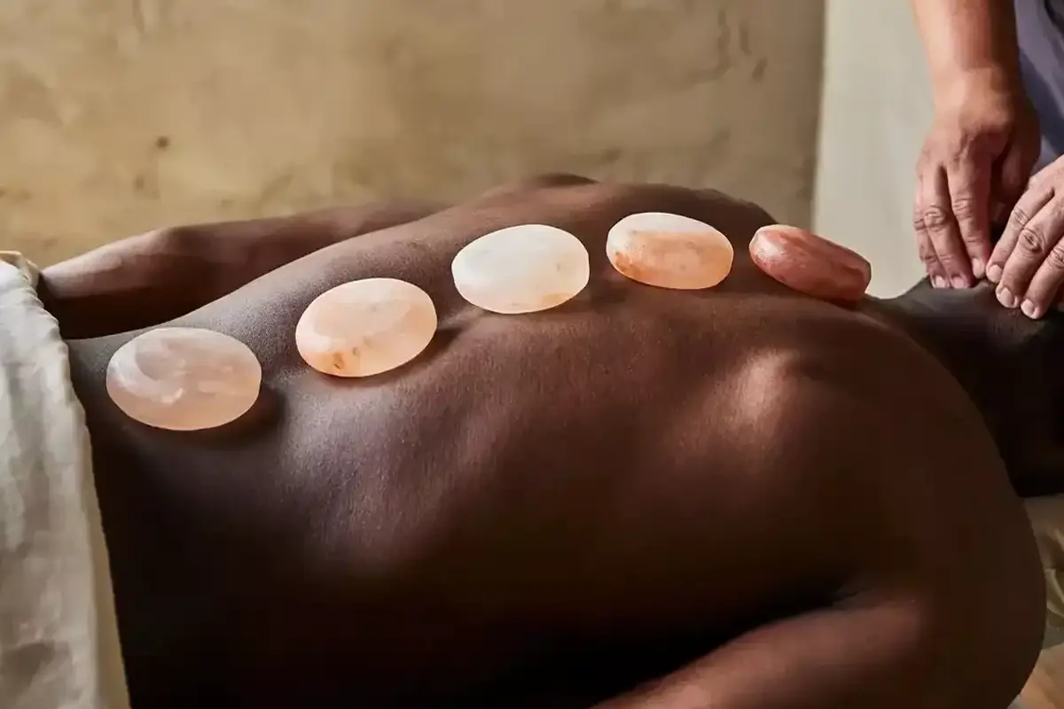 A line of Himalyan heated stones laying comfortably on a relaxing man's back.