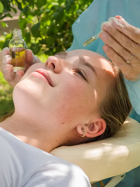CBD oil being applied to a woman's forehead. 