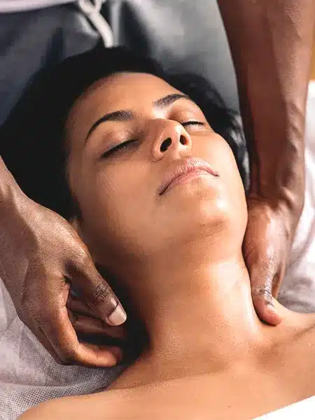 Relaxed woman lying down and receiving a neck massage. 