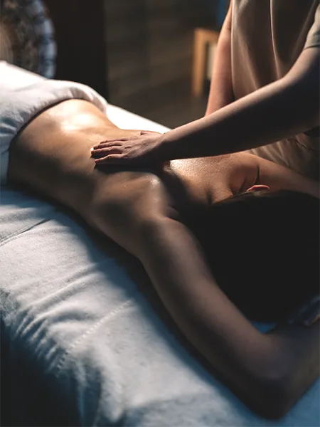 Man laying on bed with a hand massaging his shoulder.