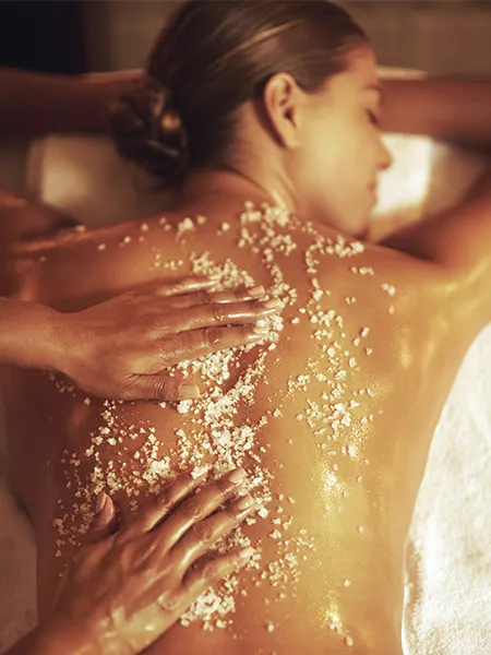 Woman getting a sugar and salt scrub and massage on her back.