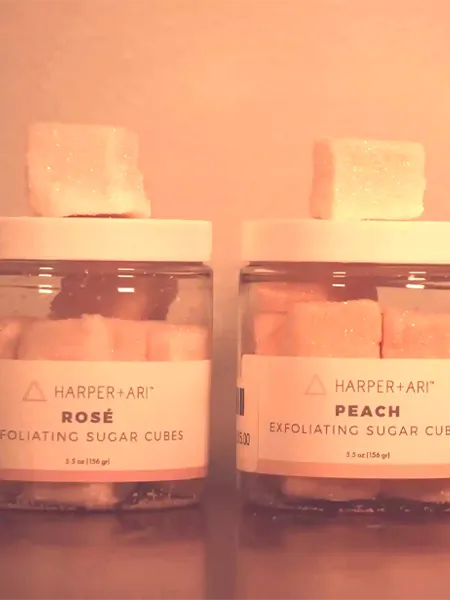Two jars of exfoliating sugar cubes, one peach flavored and the other Rose flavored.