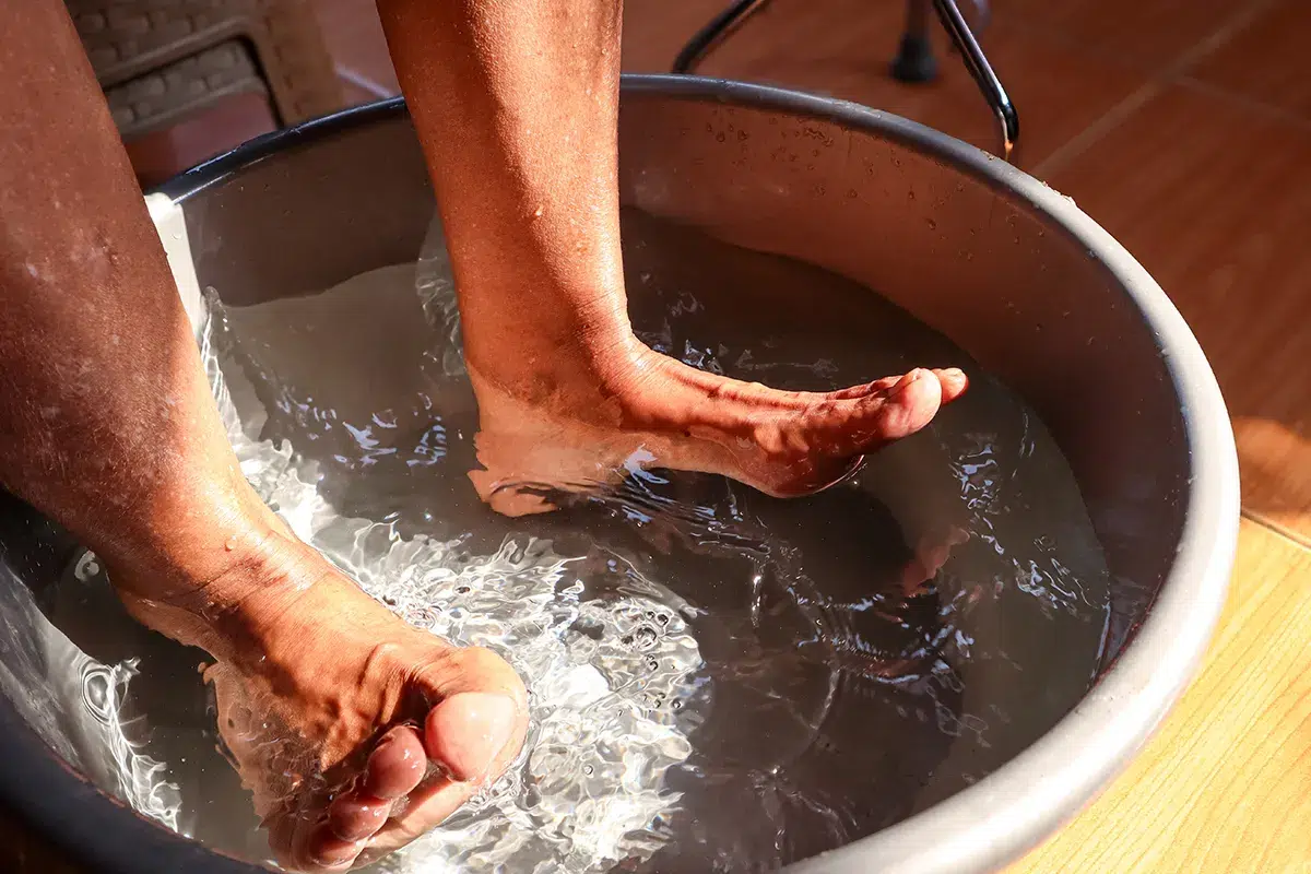 Pair of feet getting washed in a tub.