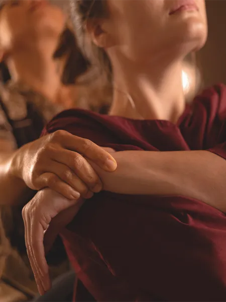 Woman stretching the arm of another woman client in front of her performing a Thai yoga technique.