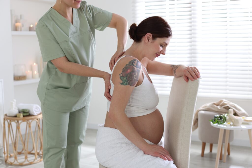 Pregnant woman receiving a prenatal massage from a therapist in a calm spa setting