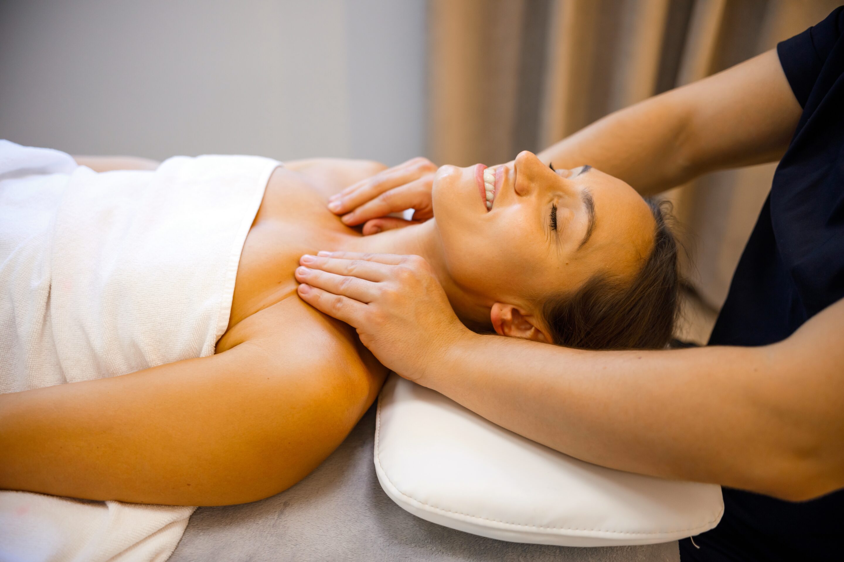Close up of woman's relaxed face getting her neck massaged by a therapist.