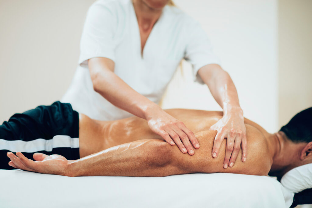 Massage therapist performing recovery massage on an athlete to relieve muscle soreness and support injury recovery