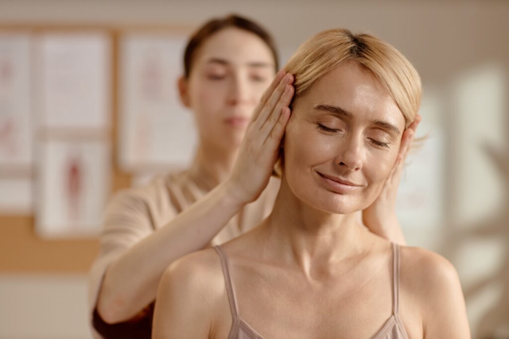 Massage therapist relieving neck and shoulder tension to support headache and neck pain relief.