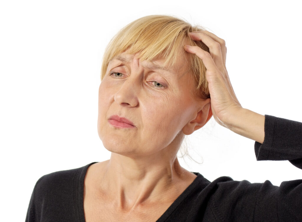 Middle aged woman holding her head due to headache pain and muscle tension, illustrating the need for massage therapy.